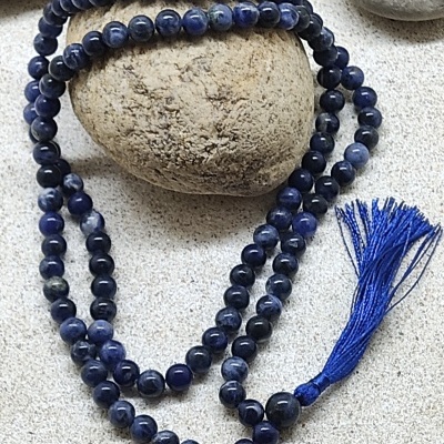 Colar de contas azuis escuras com franjas azuis sobre pedra clara