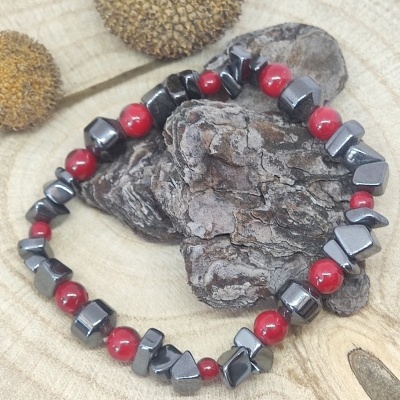 Pulseira com contas vermelhas e cinza metálico sobre fundo de madeira