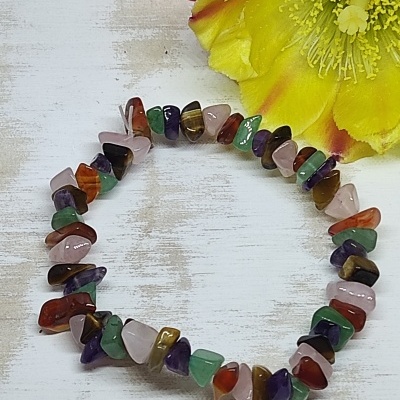 Pulseira de pedras naturais coloridas em círculo sobre superfície branca com flores