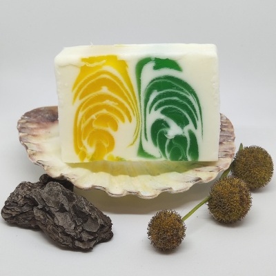 Sabonete artesanal com padrões amarelo e verde sobre concha com natureza morta