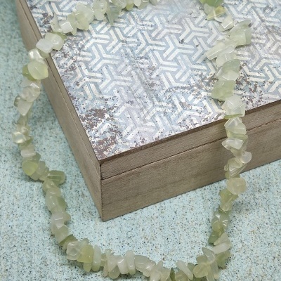 Colar de pedras naturais verdes e brancas sobre caixa decorada