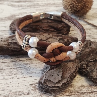 Pulseira de couro castanho e pérolas brancas sobre madeira rústica