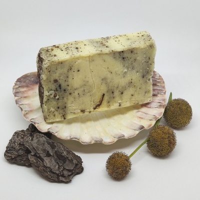 Sabonete marmoreado amarelo e castanho sobre concha, com sementes e casca de árvore