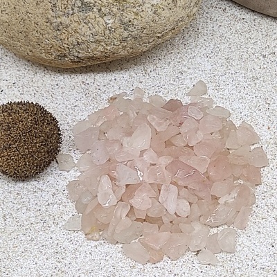 Montão de cristais rosa translúcidos ao lado de esfera marrom texturizada e pedras arredondadas