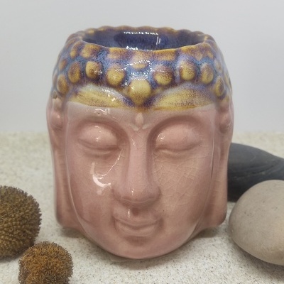Vaso cerâmico em forma de cabeça de Buda com pedras e flores secas ao redor