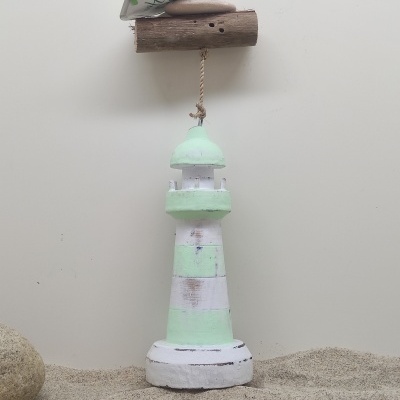 Farol decorativo de madeira verde e branco pendurado sobre areia com conchas