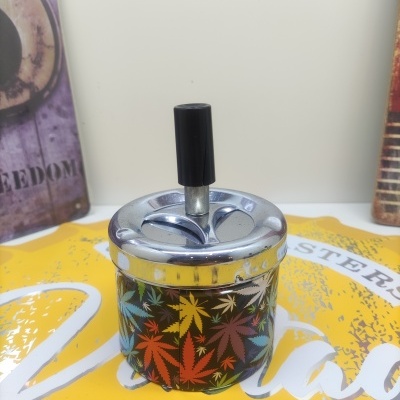 Cinzeiro de metal com padrão colorido de folhas e tampa cromada