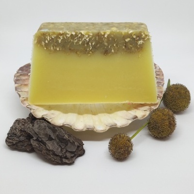 Sabão amarelo artesanal numa concha com casca e flores secas em fundo branco