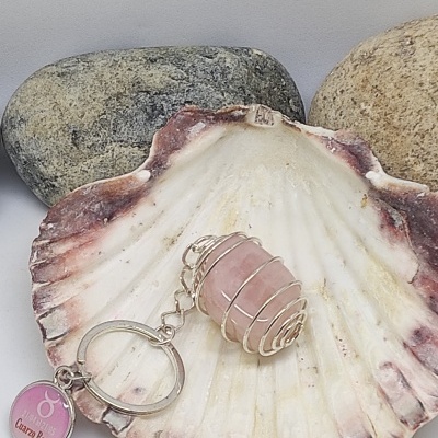 Chaveiro com pedra rosa em concha decorativa com pedras ao fundo