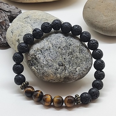 Pulseira de contas pretas e marrons sobre pedras cinzentas