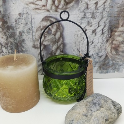 Vela castanha, suporte verde de vidro com alça preta, pedra cinzenta, fundo com imagem de cordas.