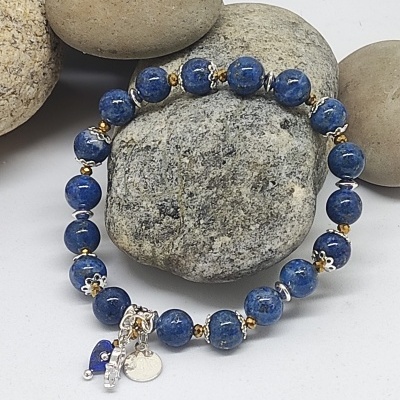 Pulseira de contas azuis com detalhes metálicos sobre pedras cinzentas e castanhas