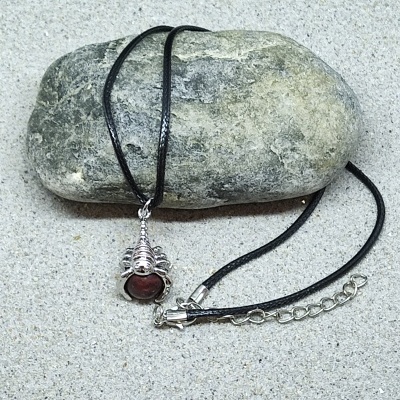 Colar com cordão preto e pendente prateado com pedra vermelha sobre pedra cinzenta