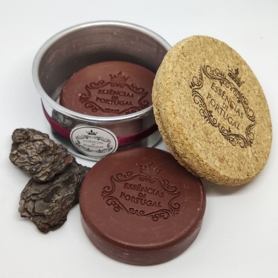 Sabonete redondo castanho com texto ESSENCIAS DE PORTUGAL em lata metálica com tampa de cortiça