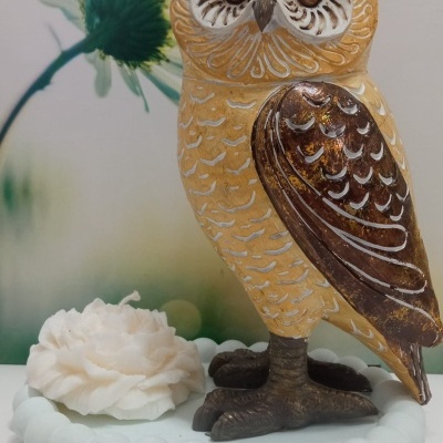Estatueta decorativa de coruja em tons castanho e amarelo com base branca e flor decorativa