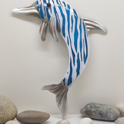 Figura de golfinho metálico azul e branco com pedras e conchas