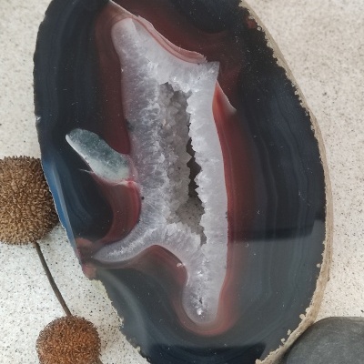 Agata cortada com interior cristalizado branco e bordas em tons de preto e vermelho