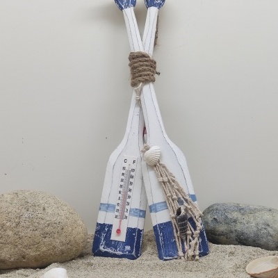 Dois remos decorativos em madeira branca e azul com termómetro e corda, em areia com pedras e conchas