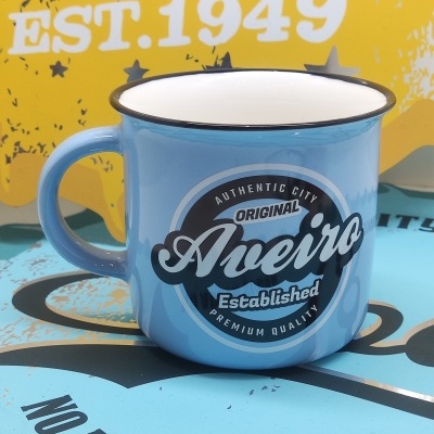 Caneca azul clara em metal esmaltado com texto Original Aveiro em fundo amarelo e azul