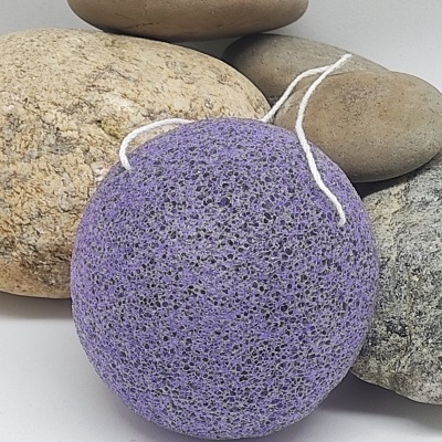 Esponja natural roxa com cordão branco sobre pedras lisas variadas