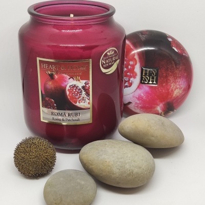 Vela perfumada em frasco vermelho com tampa de romã e pedras decorativas cinzentas e castanhas