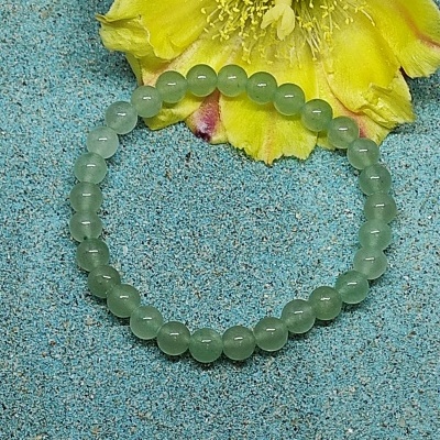 Pulseira de contas verdes com flor amarela ao fundo
