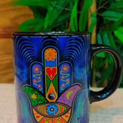 Caneca preta com padrão colorido da mão de Hamsá e olho azul