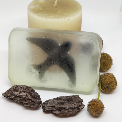 Sabonete transparente com pássaro preto embutido e vela bege com casca e frutos secos