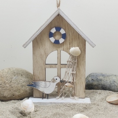 Decoração de casinha de madeira com gaivota e torre de conchas sobre areia