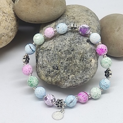 Pulseira colorida em tons pastel com contas rachadas e detalhes prateados sobre pedras cinzentas
