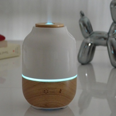 Difusor aromático em madeira clara e cerâmica branca a emitir vapor