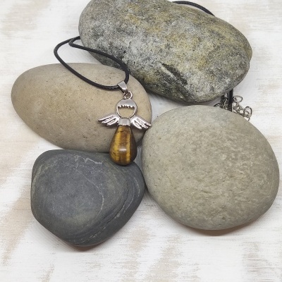 Colar com pendente em forma de anjo sobre pedras lisas