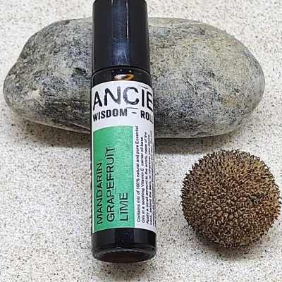 Roll-on aromaterapia preto com rótulo colorido sobre pedra e semente