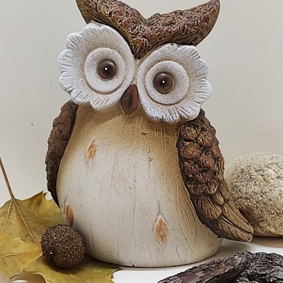 Estatueta de coruja decorativa em cerâmica castanha e bege com olhos grandes brancos e detalhes texturizados.