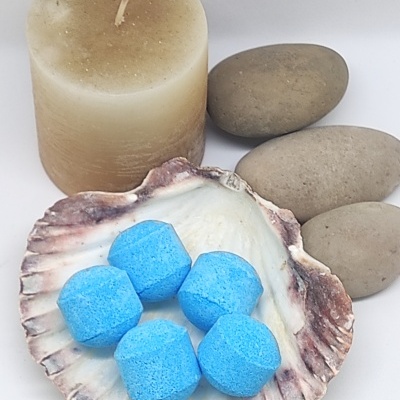 Vela bege, pedras cinzentas e concha com pastilhas azuis