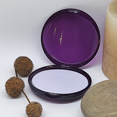 Espelho compacto roxo aberto com pedra, vela e elementos naturais castanhos