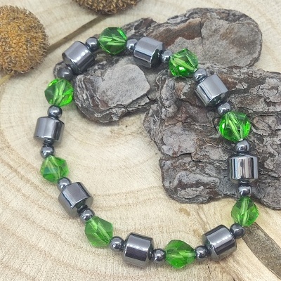 Pulseira verde e prateada sobre madeira clara com cascos secos