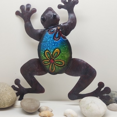 Escultura metálica colorida de rã decorativa com fundo branco e pedras ao redor