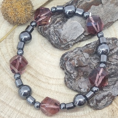 Pulseira elástica com pedras vinho e contas metálicas em fundo de madeira