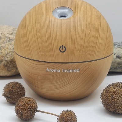 Difusor de aromas em madeira clara com texto 'Aroma Inspired' e botão de ligar