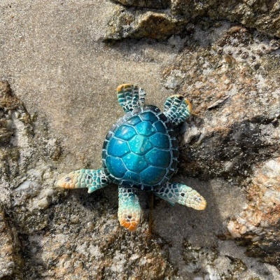 Figura decorativa de tartaruga azul sobre rocha