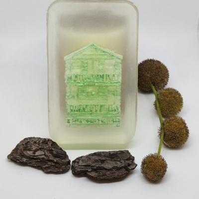 Sabonete translúcido com casa verde embutida, cascas de árvore e ramo com bolas secas.