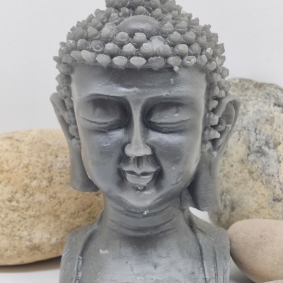 Vela cinzenta em formato de cabeça de Buda com textura detalhada no cabelo