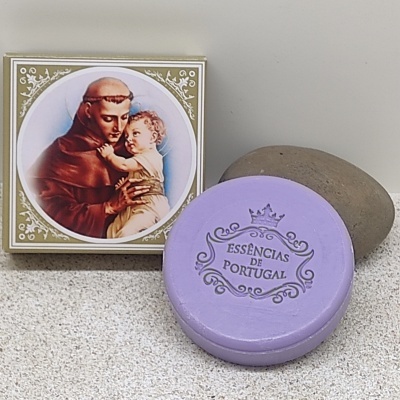 Sabonete lilás redondo com embalagem religiosa e pedra cinzenta