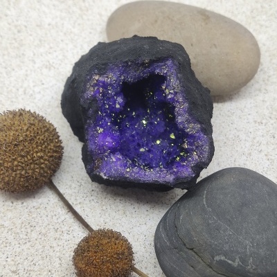 Geodo roxo cintilante com cristais dourados e pedras ao redor