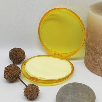 Estojo amarelo aberto com disco creme e elementos naturais ao redor