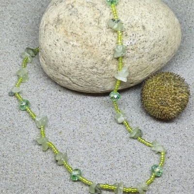 Colar verde com pedras naturais e contas sobre pedra e areia
