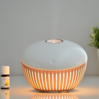 Difusor de aroma cerâmico branco com luz interior laranja numa superfície branca