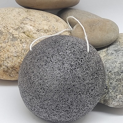 Esfregão esponja cinzento poroso com cordão branco diante de pedras