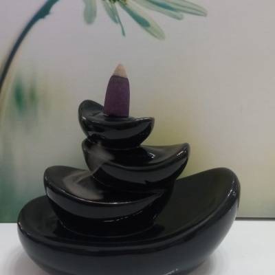 Incensário preto com cone de incenso roxo e fundo de flor branca